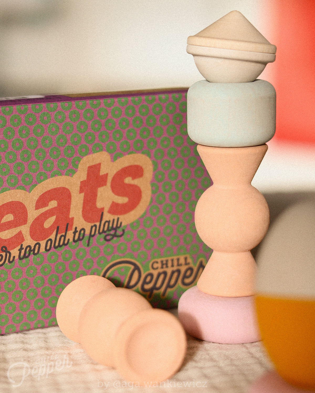 Chill Pepper Treats pastel wooden pieces balanced in a tall tower beside their patterned box, with loose pieces in the foreground.