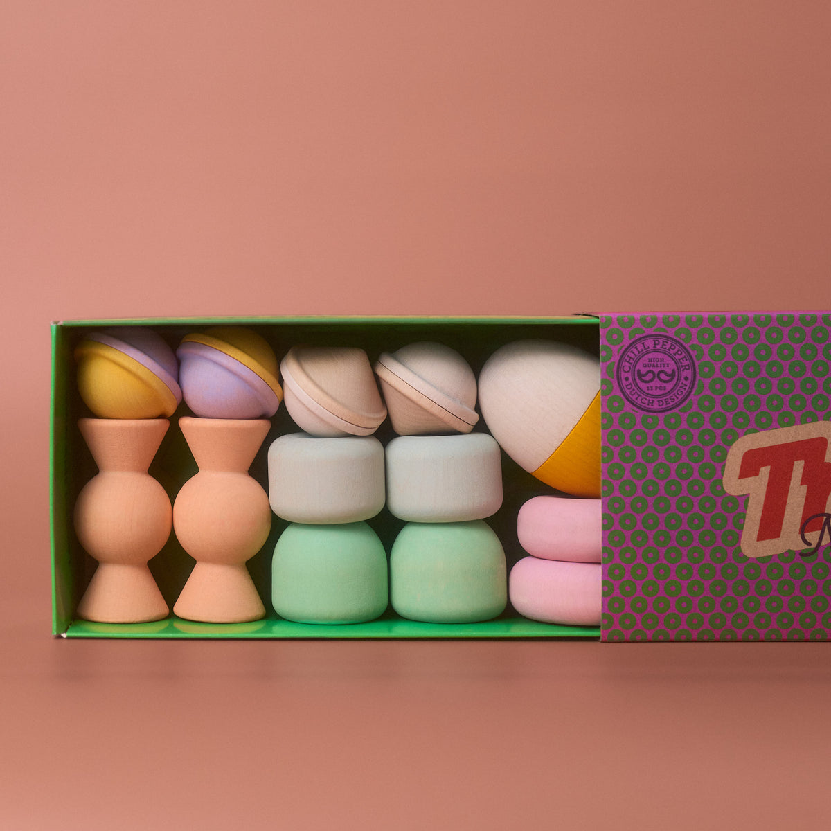 Chill Pepper Treats pastel wooden stacking and spinning toys in an open green box with a patterned sliding lid.