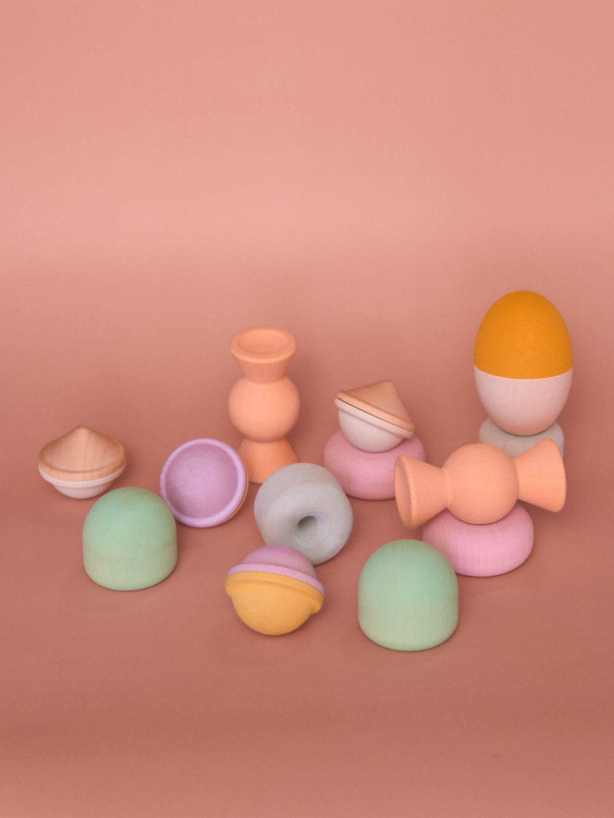 Chill Pepper Treats pastel wooden stacking and spinning toys arranged in small stacks and individually on a pink background.