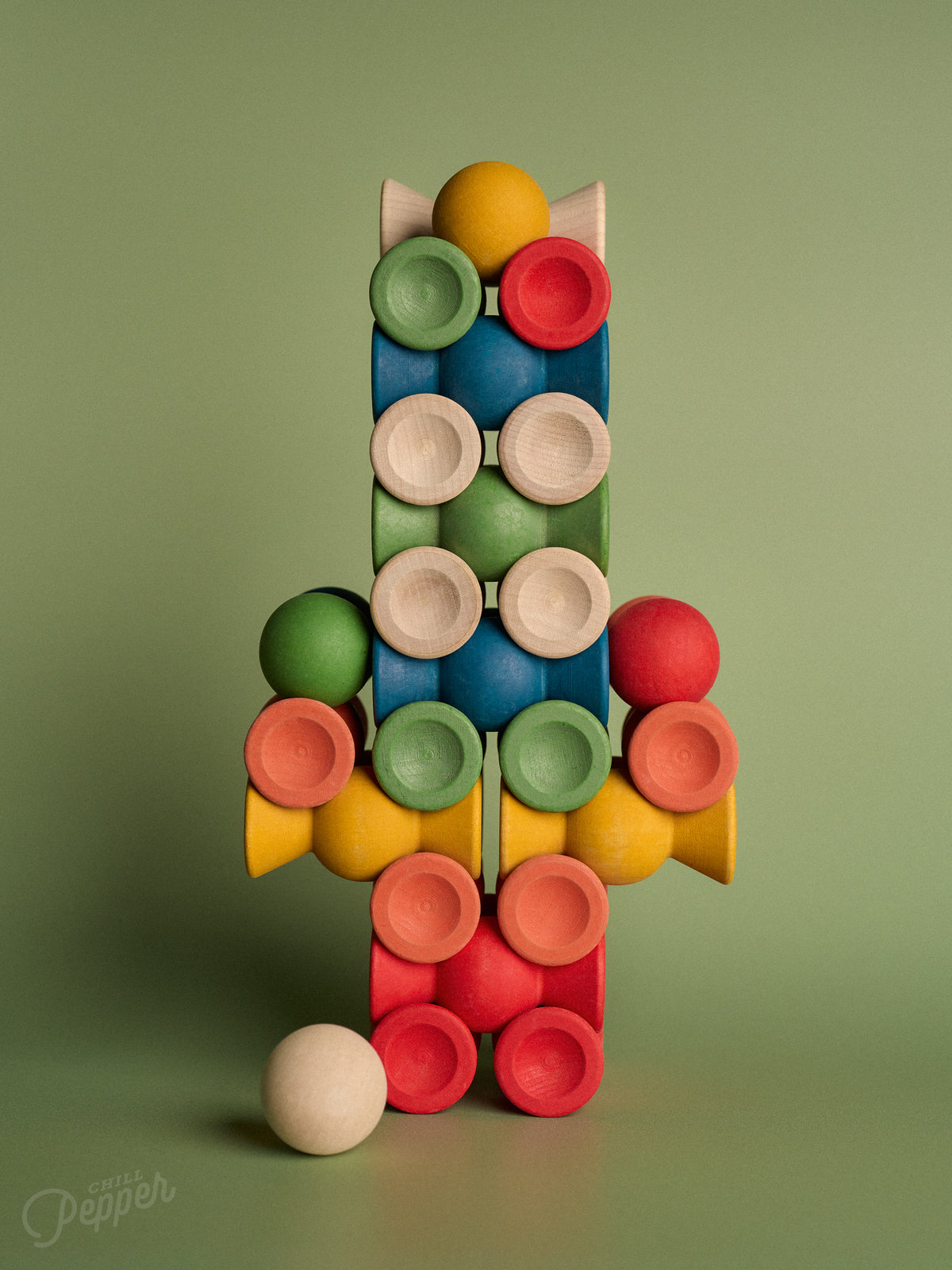 Overhead view of Chill Pepper Sweets Forest Fruits wooden pieces arranged in a symmetrical pattern on a green background.