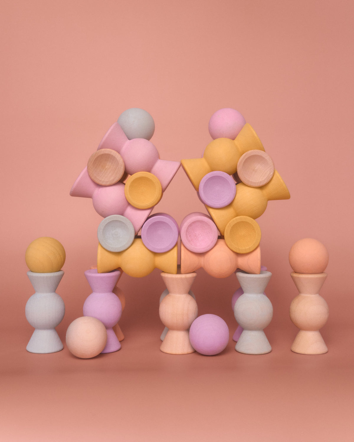 Chill Pepper Sweets Peachy Pastels wooden sweets and gumballs balanced in a branching structure on a pink background.